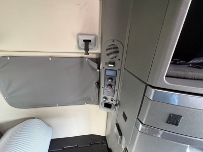 Interior of Volvo VNL truck cab showing side panel with control module, speaker, and switch panel near door.