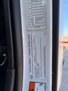 Truck door jamb label showing vehicle information and chassis paint details on a Volvo VNL124 wheel housing area.