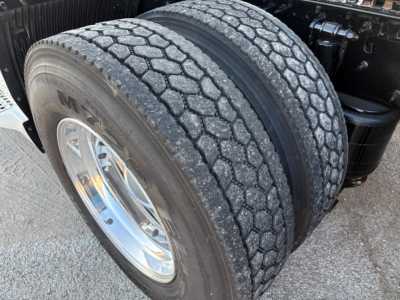 Volvo VNL64T860 truck dual rear tires close-up showing tread pattern and wheel, with part of suspension and frame.