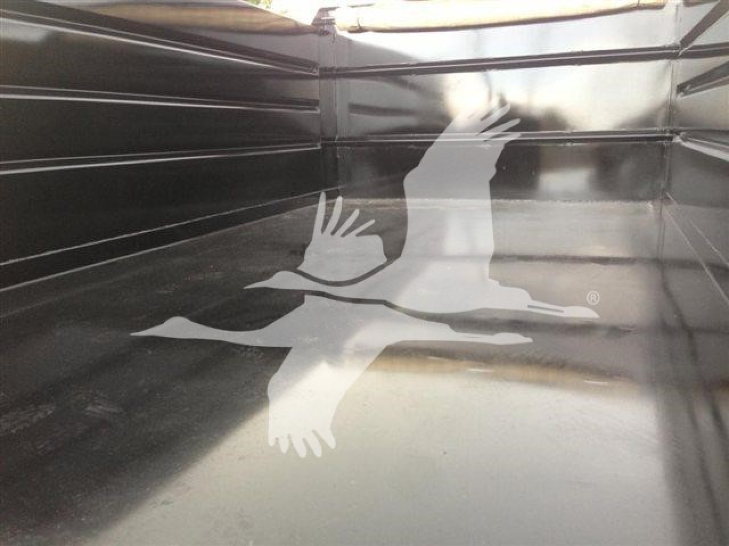 Dump truck bed interior showing a decal of two birds in flight.