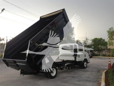 Dump truck with a raised black dump bed attached to a white cab, loading position at an angle.