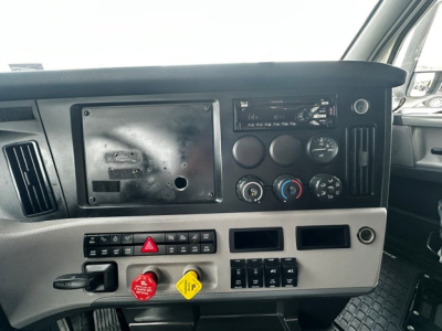 Dashboard of a Freightliner Cascadia 126 truck showing instrument cluster, vents, switch panel, and yellow and red hazard controls.