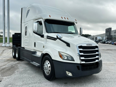 Freightliner Cascadia 126 truck in white view from front-left shows cab: chrome grille, dual headlights, side mirrors, and sleeper cab with aerodynamic design.