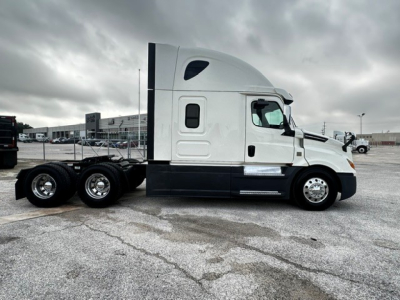 Freightliner Cascadia 126 sleeper cab tractor side view showing white cab and black chassis with dual rear axles.