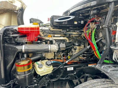 Freightliner Cascadia 126 engine bay showing coolant reservoir, various colored wiring, hoses, and components.