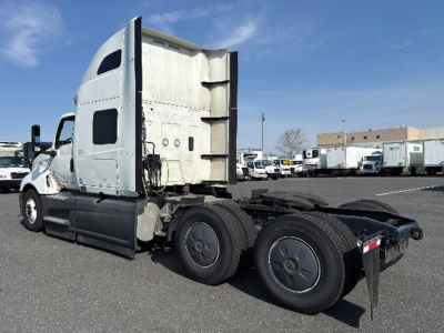 Truck side view showing a white International LT625 conventional sleeper tractor with two rear axles and fifth wheel in a parking lot.
