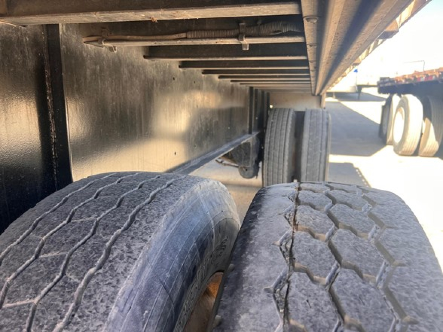 Truck trailer undercarriage with dual rear tires and frame showing underside of flatbed (Transcraft) and side components.