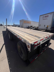 Trailer deck of a 2022 Transcraft spread air combo flatbed showing long wooden/metal deck and dual rear axles with taillights.