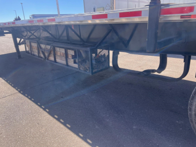 Trailer side view showing steel frame, storage cage, and underside components of a used Transcraft spread air combo flatbed.