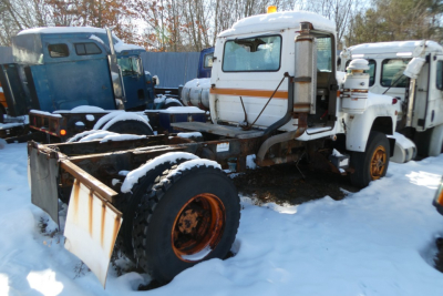 Mack R690T cab and chassis with front cab and snow-covered frame, orange wheels, and spare wheel mounting visible.
