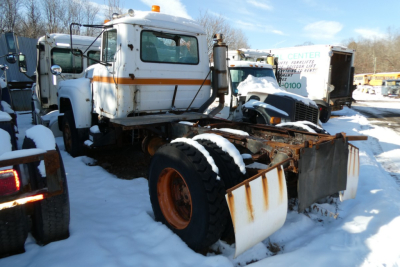 Mack R690T cab and chassis in-row with snow on ground, showing front cab, large front tires, rusted frame, and snowplow-like attachment.
