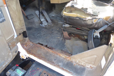 Mack R690T cab interior showing driver seat and floor with worn trim and exposed metal edge.
