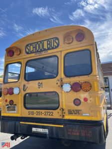 Rear view of a yellow 2015 Blue Bird Vision school bus with 'SCHOOL BUS' sign, bus number 91, contact number, and multiple rear lights visible.