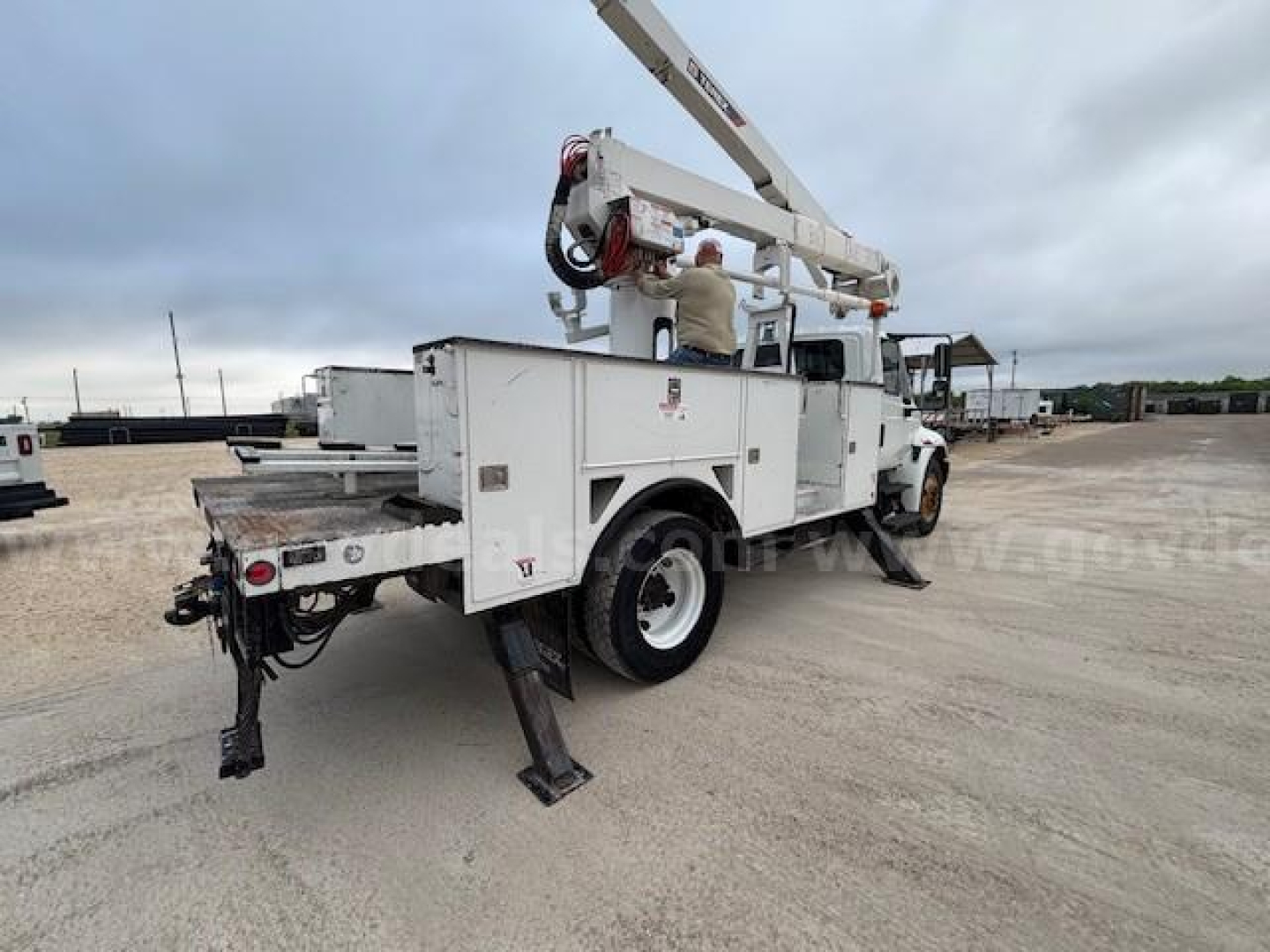 Bucket truck with boom lift in working condition and stabilizers deployed.