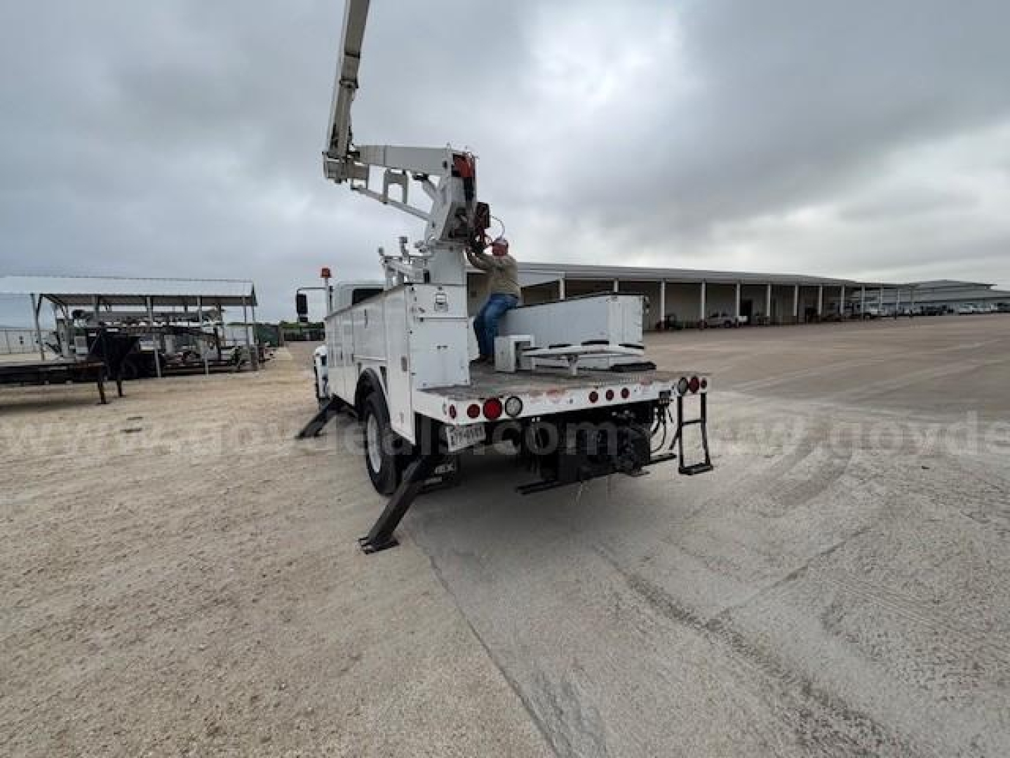 Back of 2019 International DuraStar 4300 bucket truck with crane arm extended, rear view showing stabilizers and utility bed.