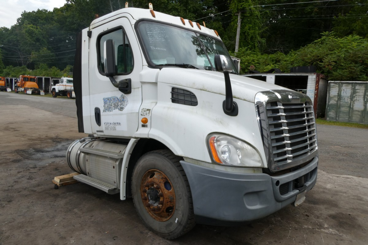 Truck cab showing 2012 Freightliner Cascadia 113 daytime exterior with front grille, headlight, and side mirror, white cab, stock number plate visible.