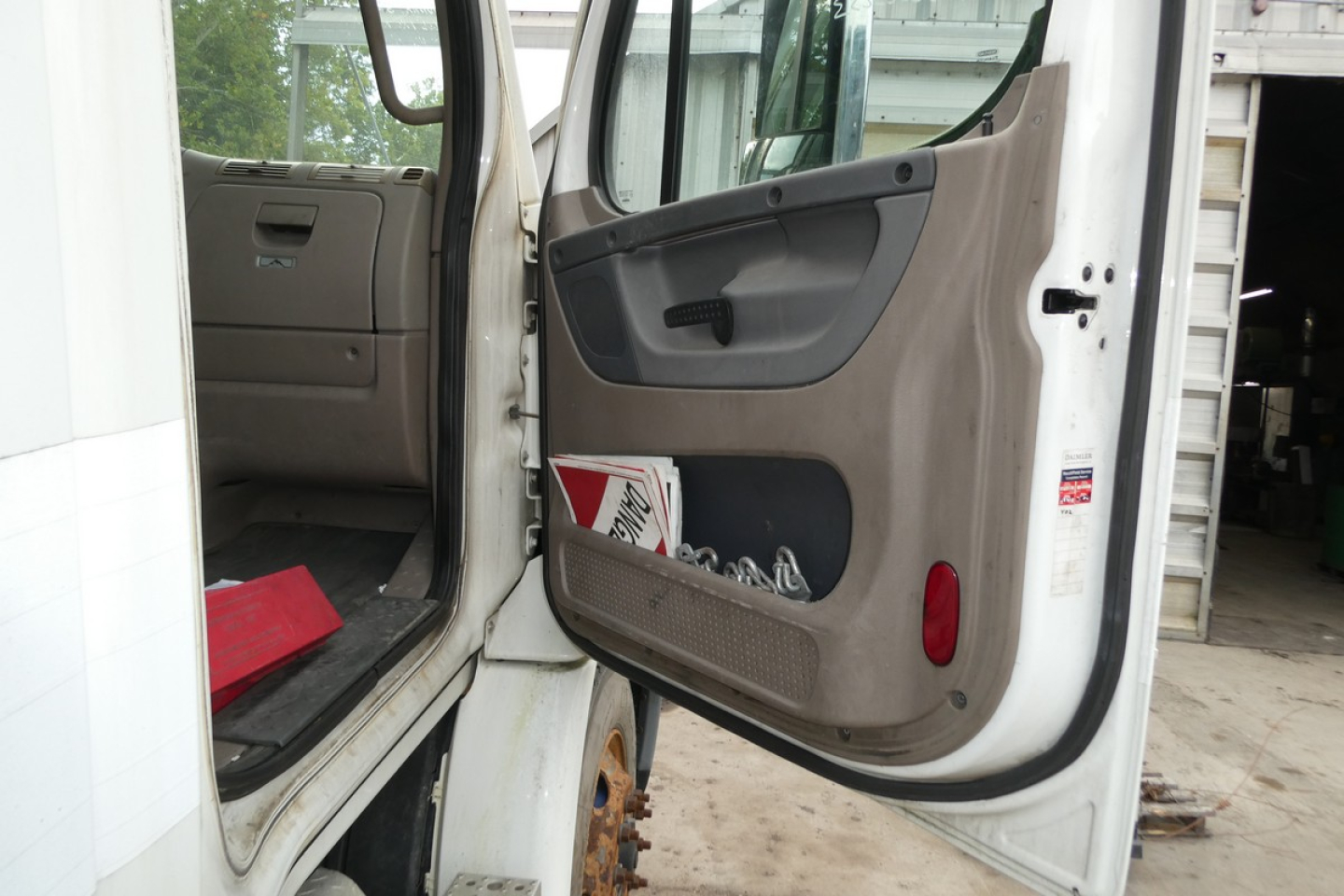 Truck cab interior door area of a 2012 Freightliner Cascadia 113 conventional daycab showing open door and entry step