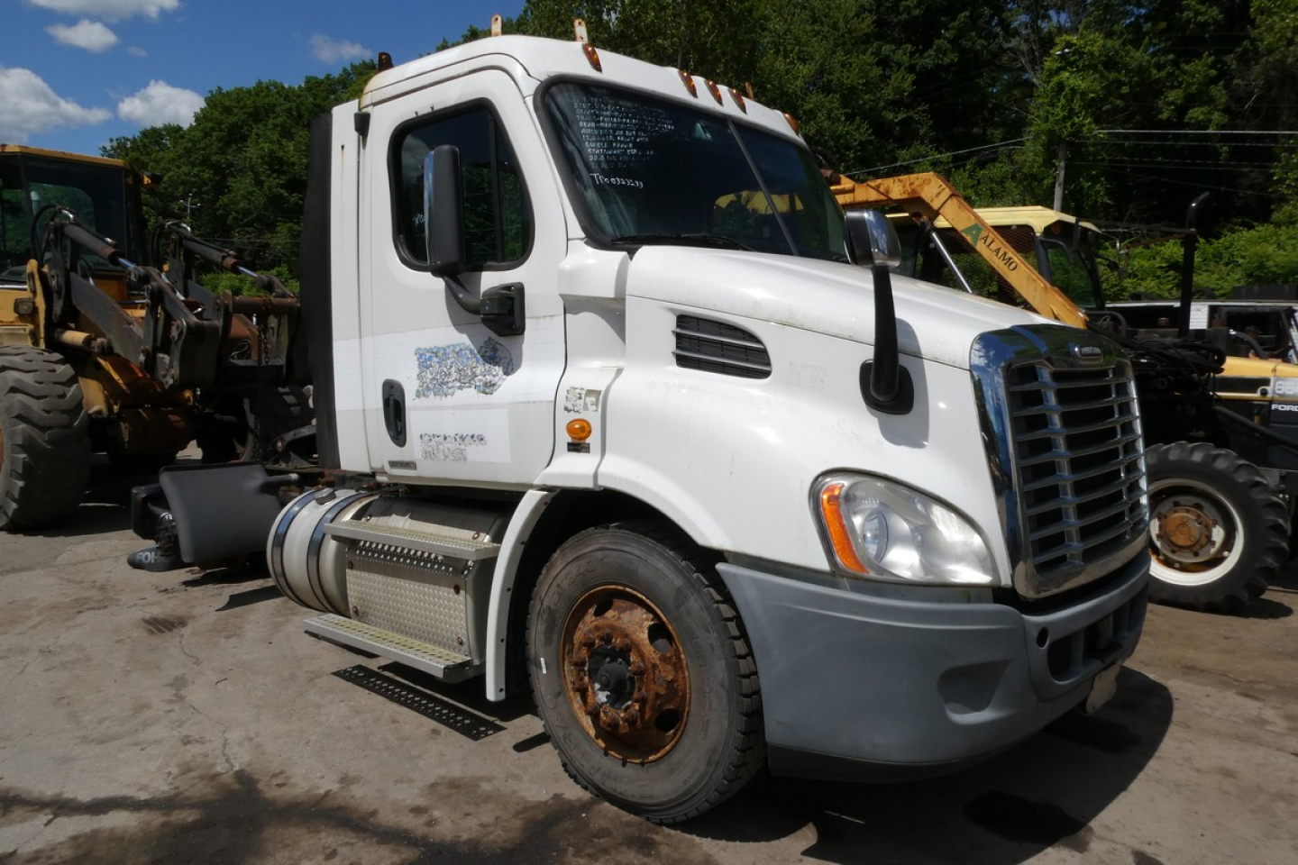 Freightliner Cascadia 113 daycab truck in view showing front and side, white cab with black grille, rusty wheel, and fuel tanks.
