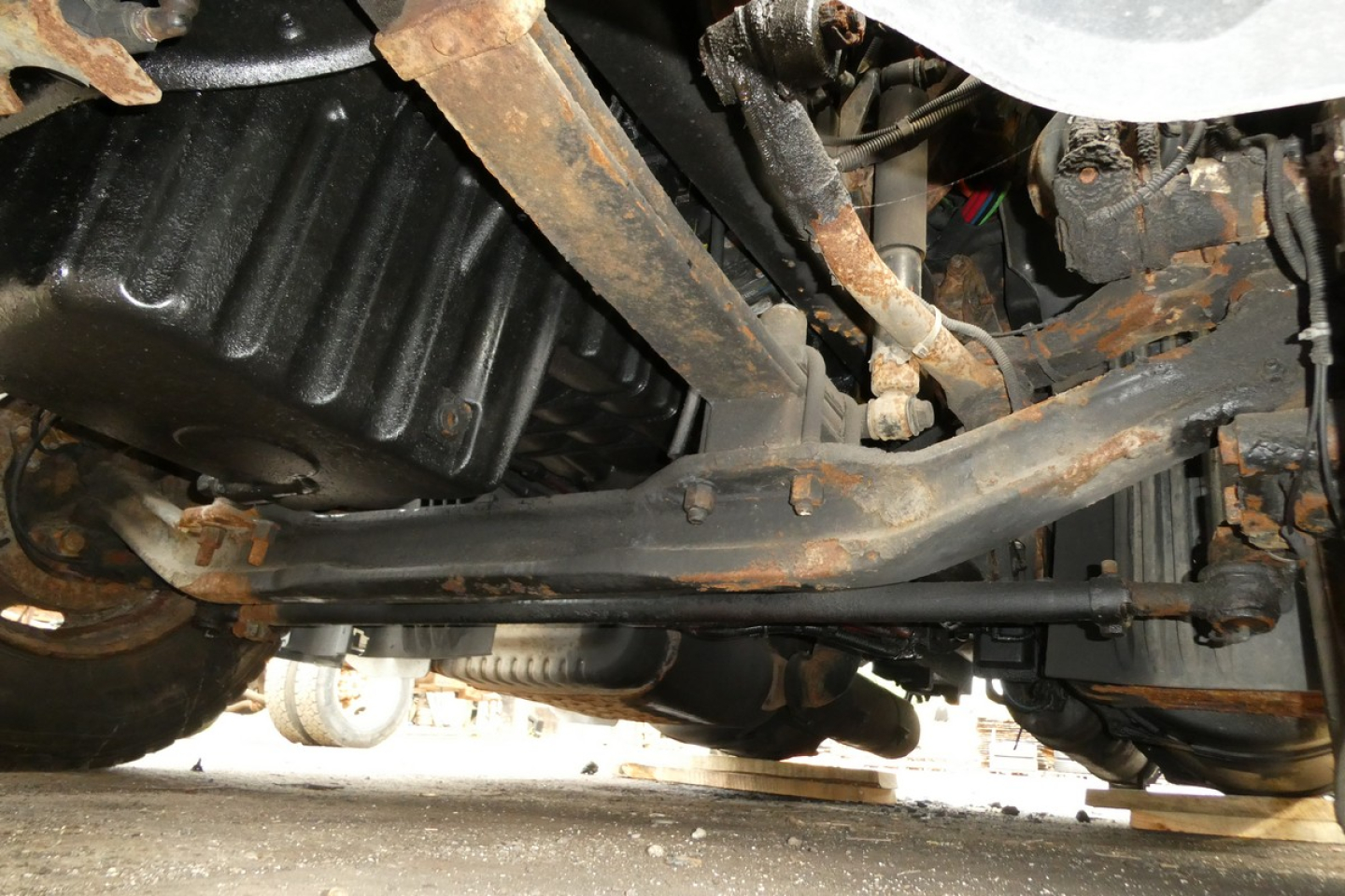 underbody view of 2012 Freightliner Cascadia 113 truck showing suspension components and drivetrain underside with rust on metal brackets