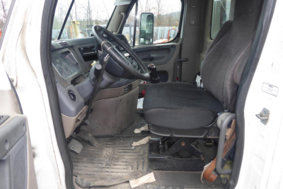 Cab interior of 2012 Freightliner Cascadia 113 daycab showing steering wheel, driver seat, dashboard, and entry door.