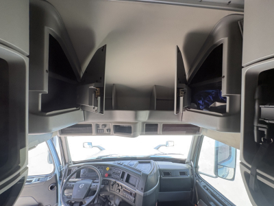 Cab interior of Volvo VNL64T760 showing overhead storage compartments and dashboard area with steering wheel and front windshield