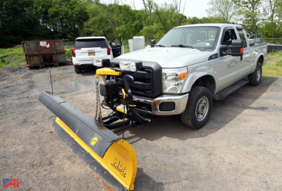 Ford F-250 pickup with front mounted snow plow attachment in a gravel lot.
