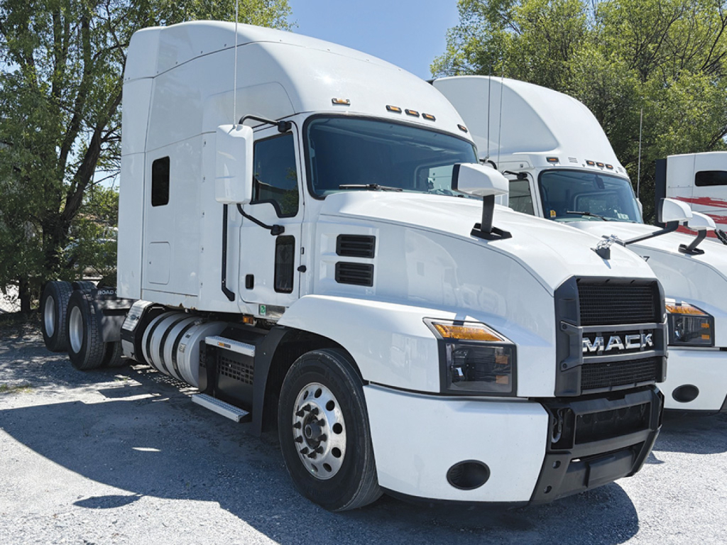 Truck cab front-left view of a white 2021 Mack sleeper tractor showing Mack grille and fuel tanks.