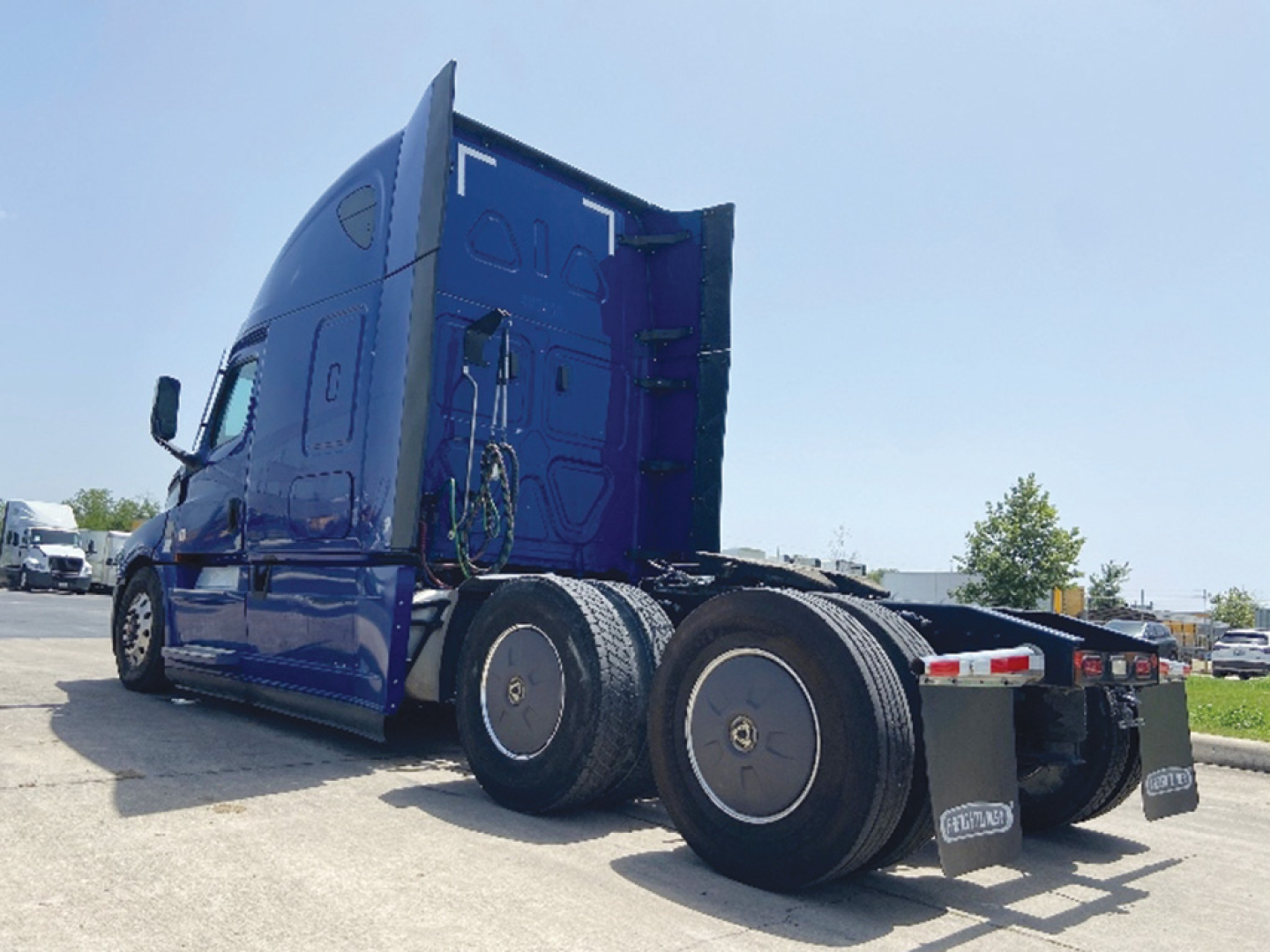 Truck cab and rear wheels of a 2022 Freightliner Cascadia126 conventional sleeper tractor showing side profile and rear fenders