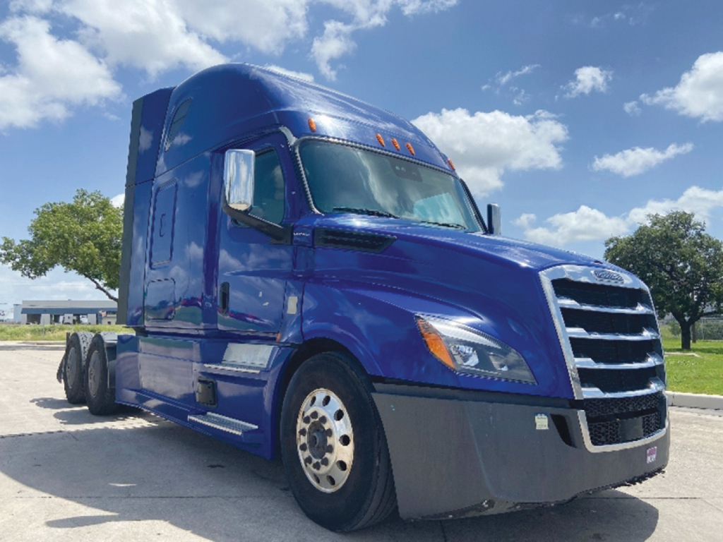 Truck semi-trailer tractor with deep blue cab, Freightliner Cascadia 126 design, front grille and headlights visible, side mirrors and wheel rims clear.