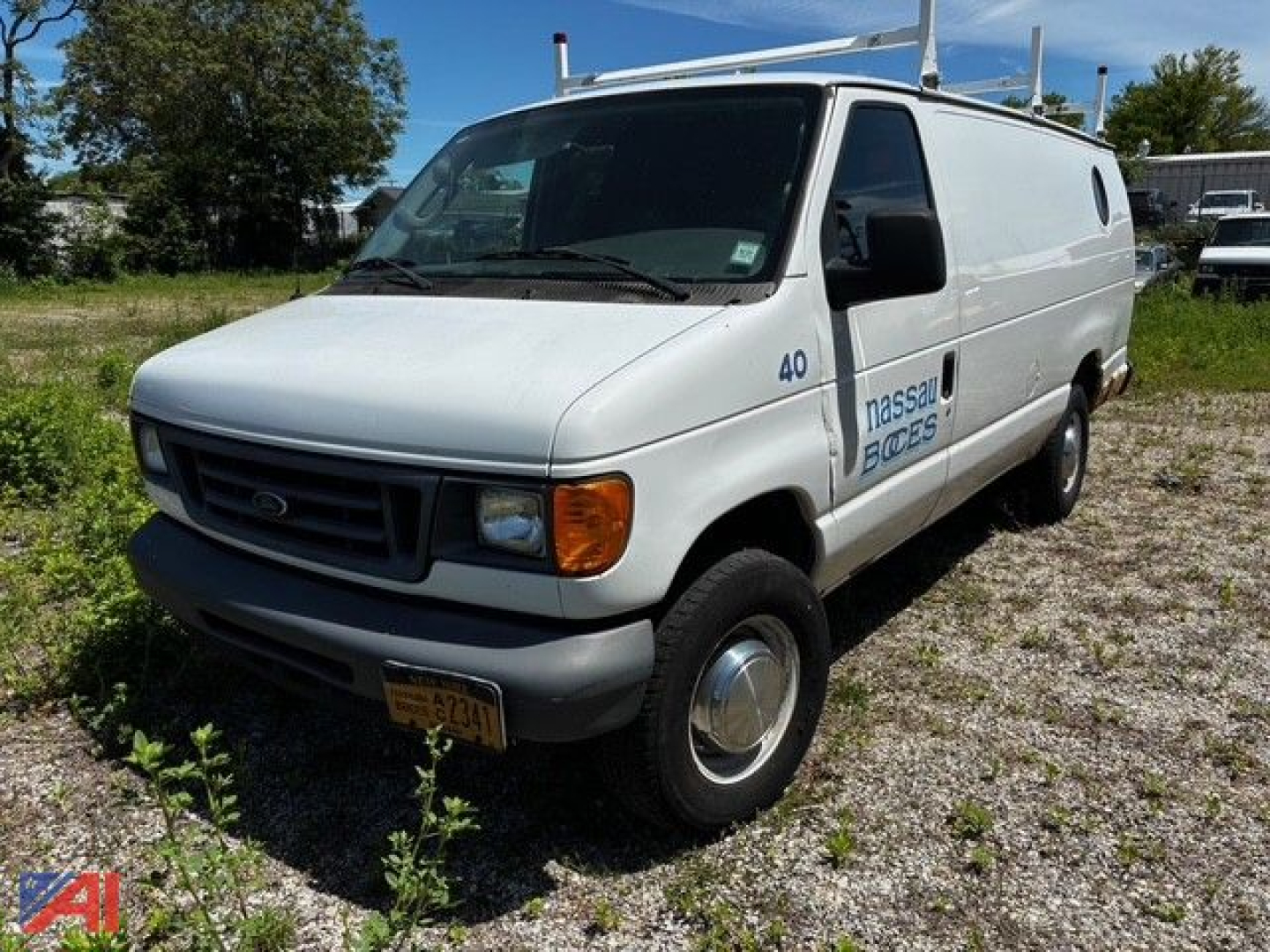 Ford E350 cargo van in-service showing front-left view with NASSAU-BOYS or BOCES logo on side and roof ladder rack.