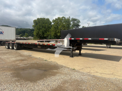 2015 Transcraft DTL-3000 drop deck trailer with extended flatbed and landing gear visible; there is a raised black deck, white support legs, and a partial trailer in background.