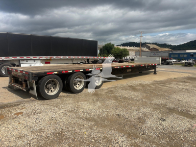 Transcraft DTL-3000 drop deck trailer showing long flatbed with dual rear axles and wooden deck.