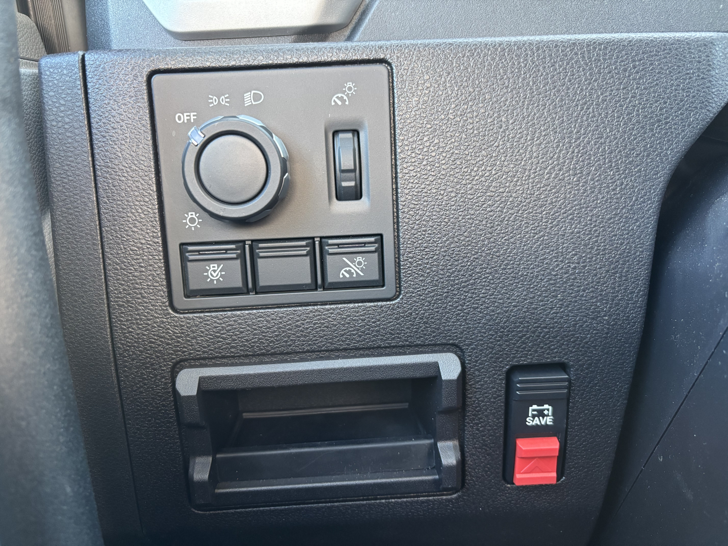 Dashboard panel with headlight knob and switches in a Mack AN64T truck view, plus a small red toggle labeled SAVE on the right and an open storage slot below.