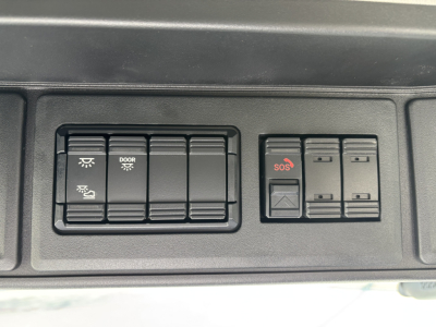 Dashboard controls and switches panel in a Mack AN64T showing door/lighting switches and SOS/emergency button