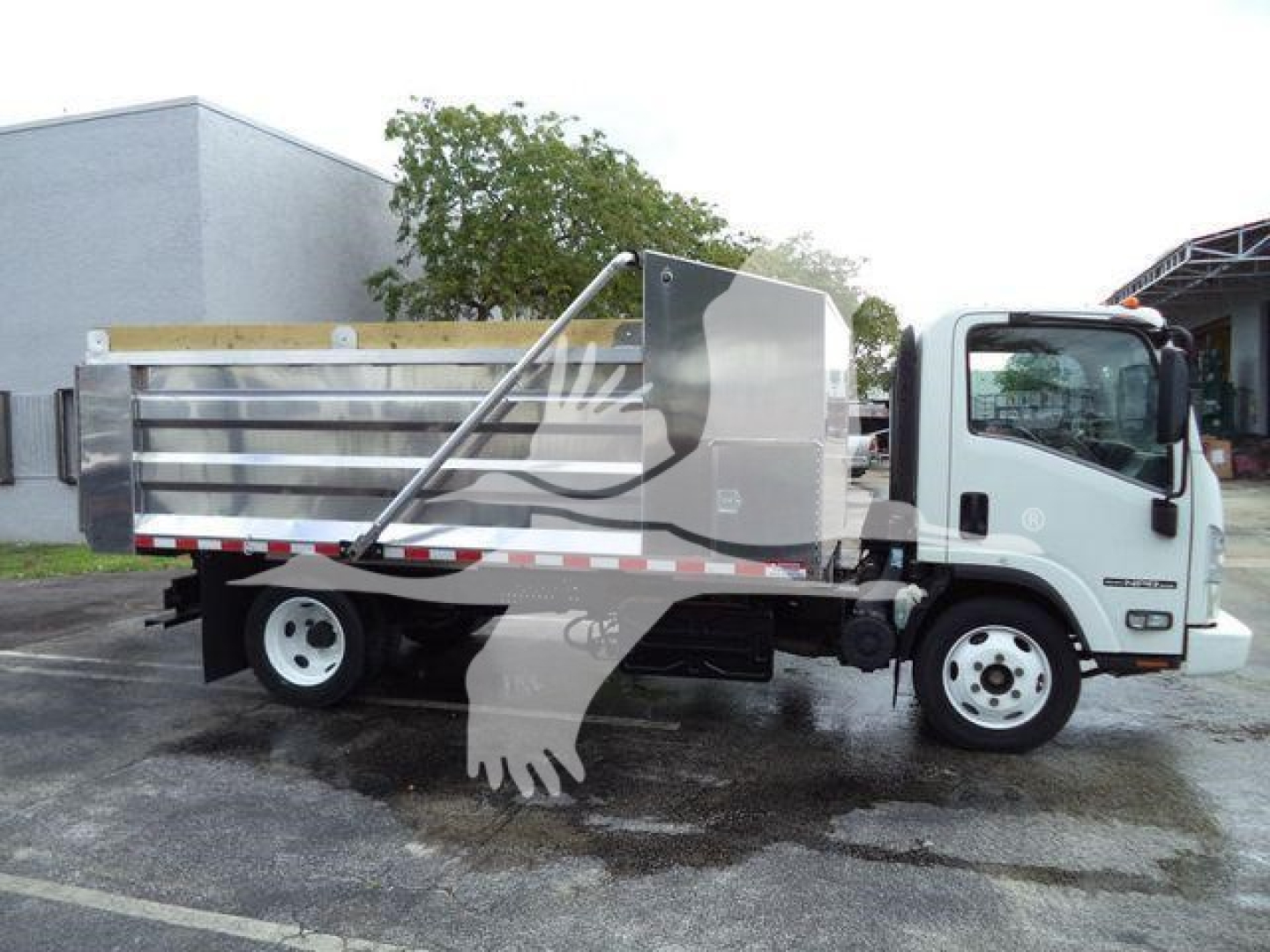 Isuzu NPR XD dump truck side view with aluminum dump body and white cab.