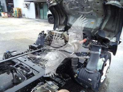 Isuzu NPR XD truck chassis and exposed engine compartment with cab removed, showing components and hoses.