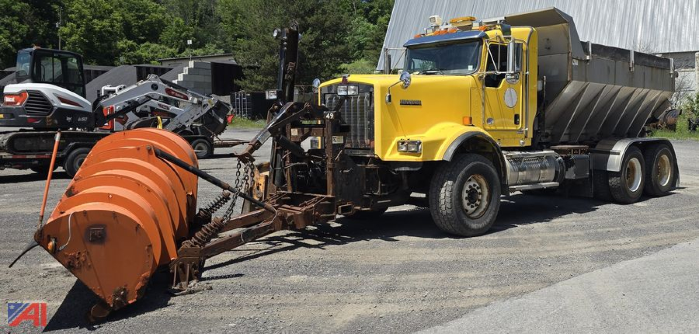 Kenworth T800 dump truck with large orange snowplow attachment in front, yellow cab, dumping bed, side mirrors, and warning lights.