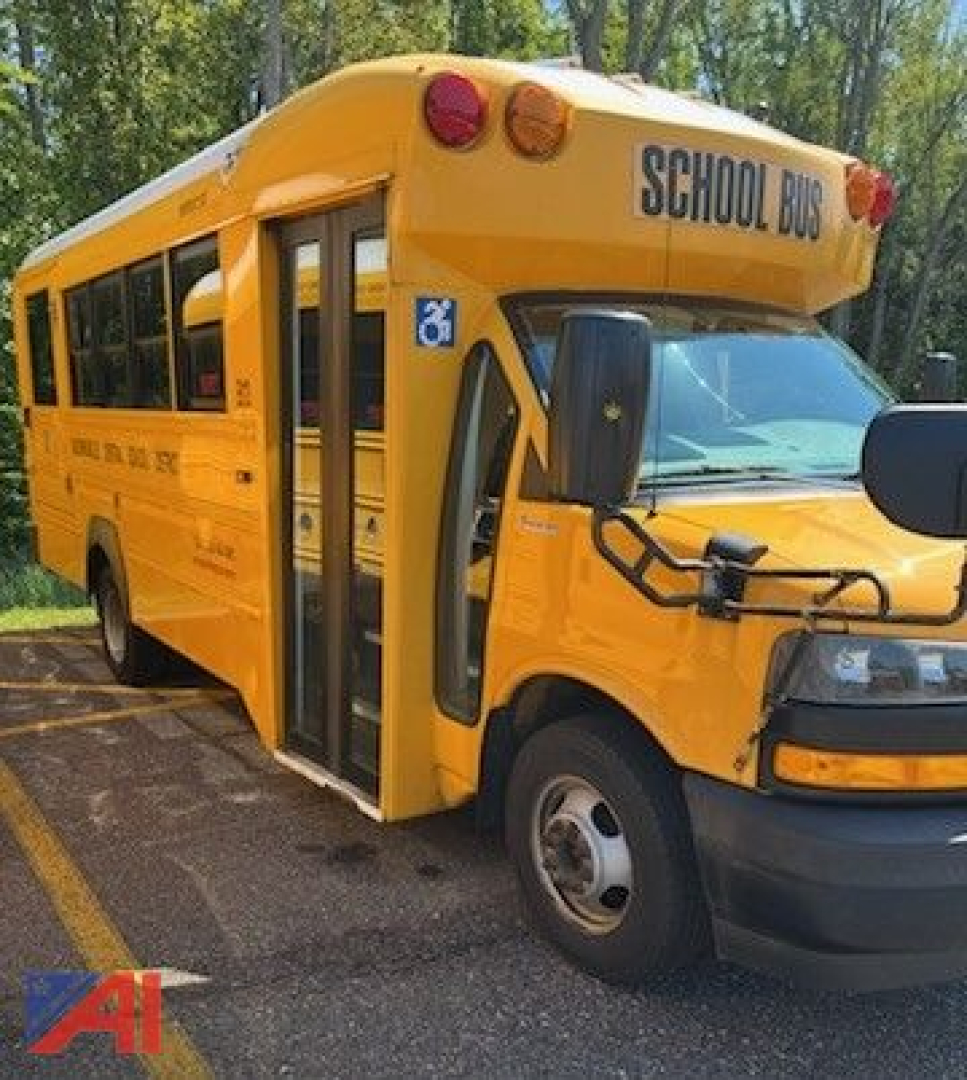 School bus with wheelchair lift, side view, 2018 Chevrolet Trans Tech Express mini-bus, yellow color, ‘SCHOOL BUS’ sign on front, wheelchair-accessible logo visible