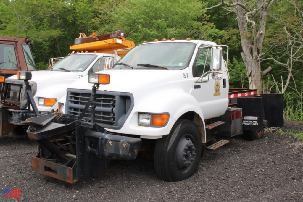 Ford F-750 Super Duty cab and chassis truck in white, front view, utility equipment on a tow setup with black front bumper and winch, used vehicle.