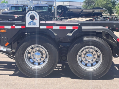 Mack GR64B rolloff truck wheel area with dual rear axles, metal frame, and chrome hubcaps visible.
