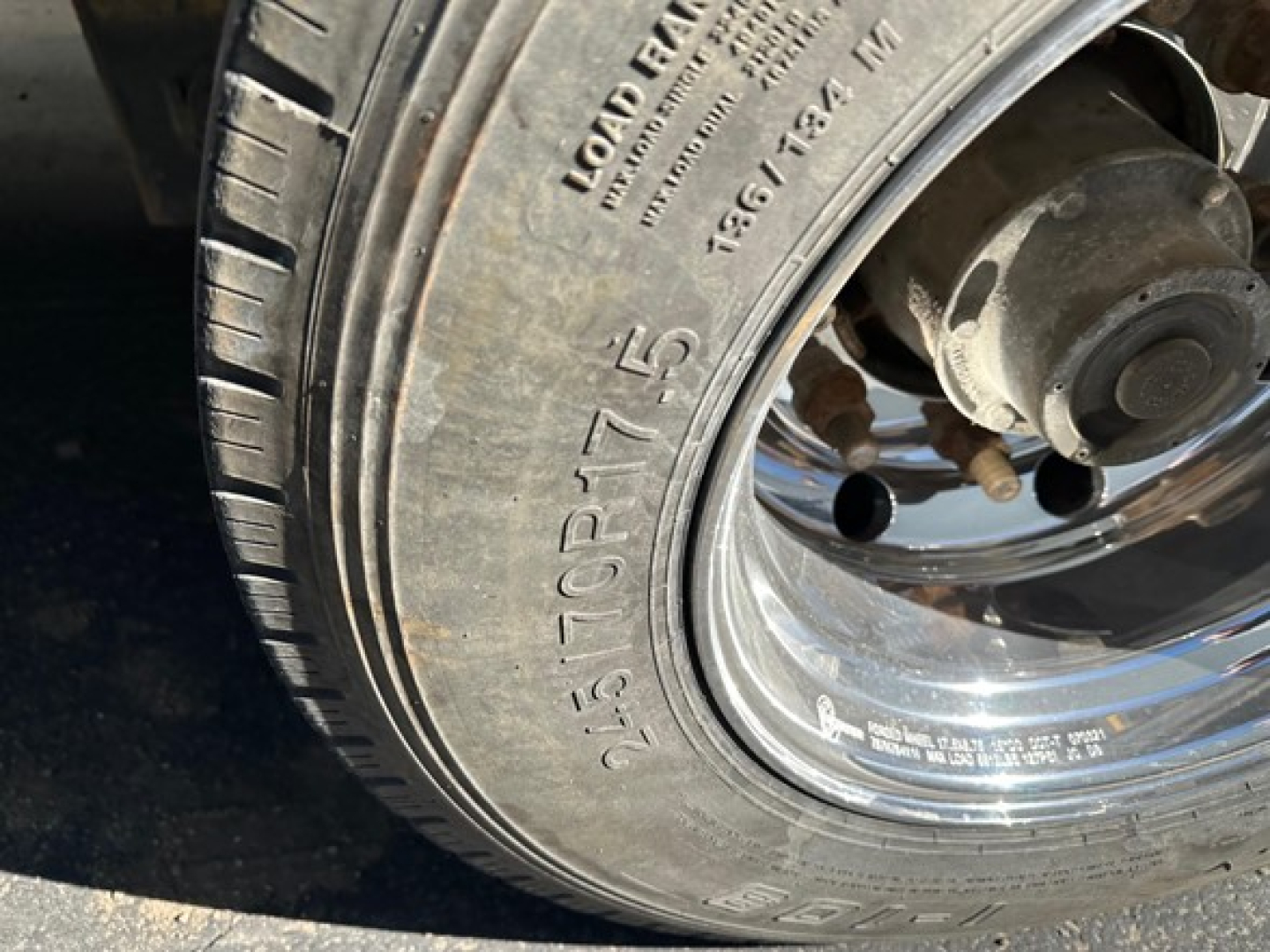 Rear wheel and tire of a trailer showing tire markings including 215/75R14.0, Load Range D, and metal rim with hub assembly.