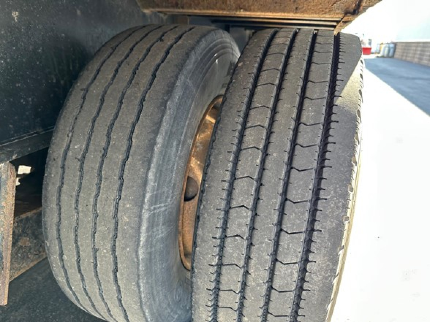 Dual rear trailer wheels showing treaded tires on Transcraft DTl trailer axle with metal rims.