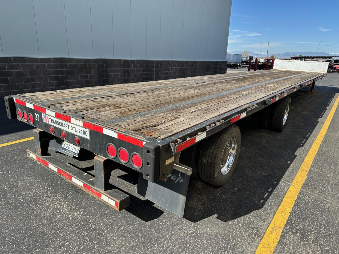 Trailer with a long wooden deck showing Transcraft flatbed/trailer rear and taillights.
