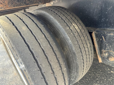 Trailer wheel assembly with dual tires on a drop deck trailer showing tread and sidewall details.