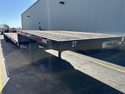 Flatbed trailer deck showing 27 and 150114240297 VIN plate with Transcraft branding visible in a yard.