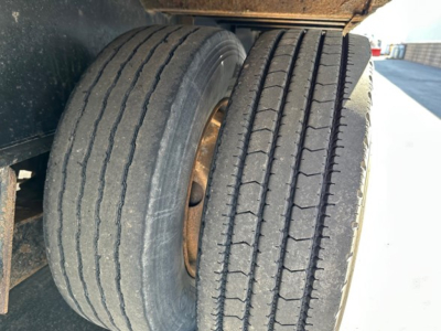 Dual rear trailer wheels showing treaded tires on Transcraft DTl trailer axle with metal rims.