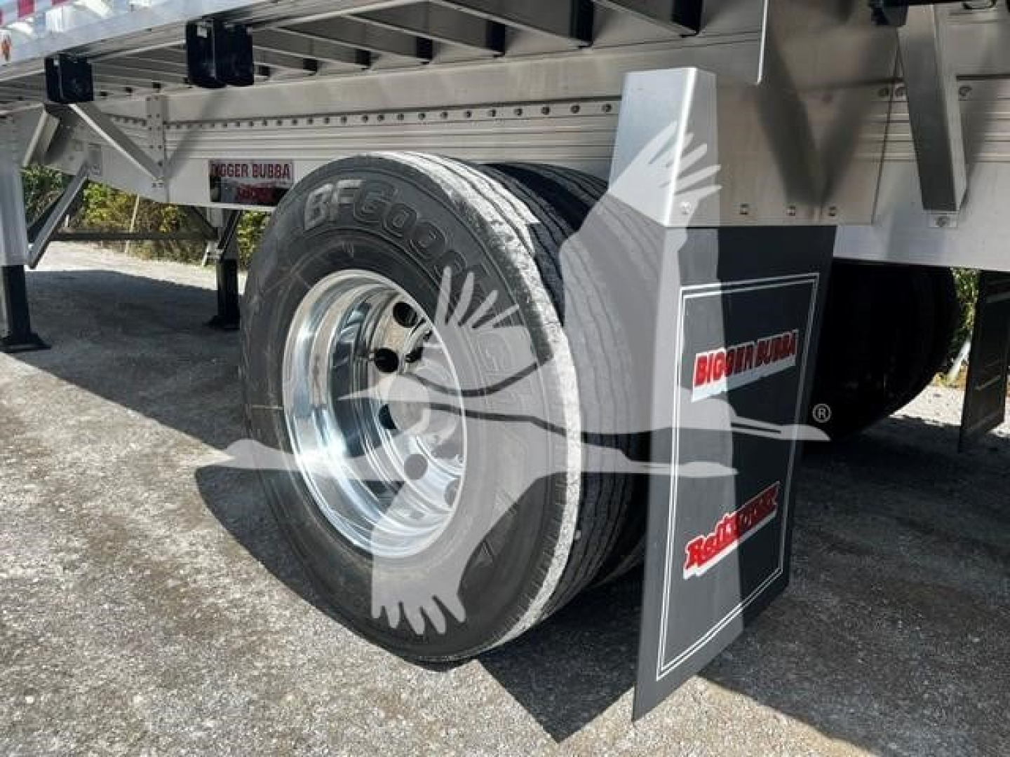 Trailer wheel and mud flap showing Big Bubba branding and BF Goodrich tire on a flatbed trailer (new) with chrome wheel and metal frame.