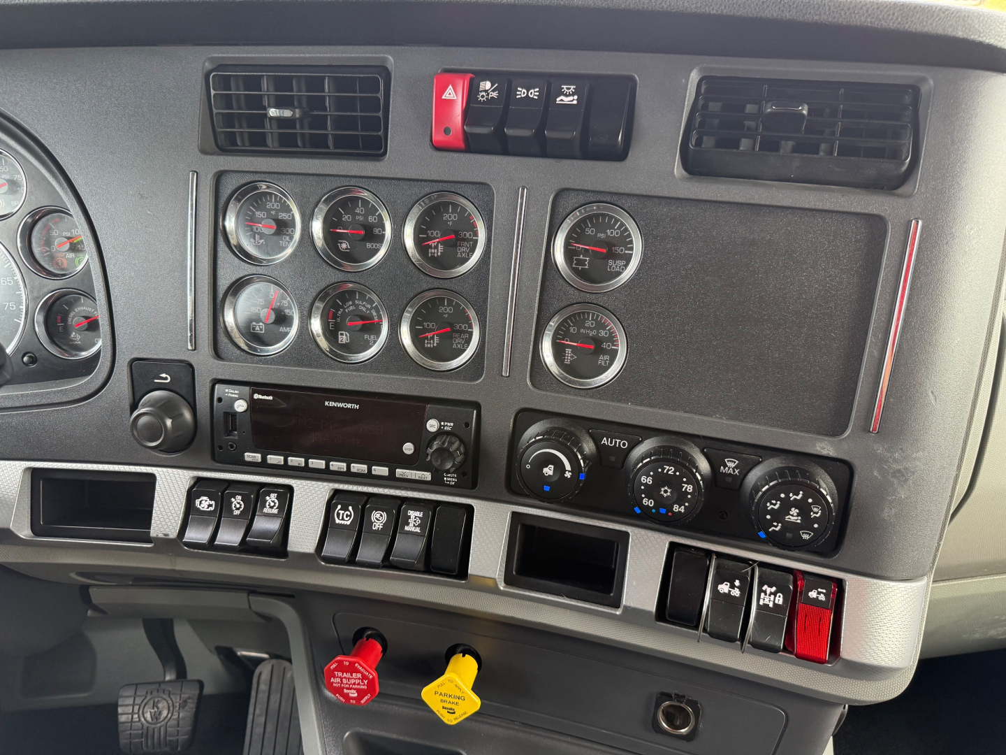 Kenworth T680 dash panel showing gauges, switches, and climate controls with red and yellow tags.