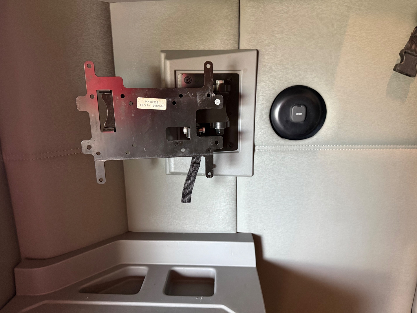 Incorrectly positioned mounting bracket and panel in a Kenworth T680 interior dash area showing a metal plate with cutouts and a small label, mounted near a circular knob.
