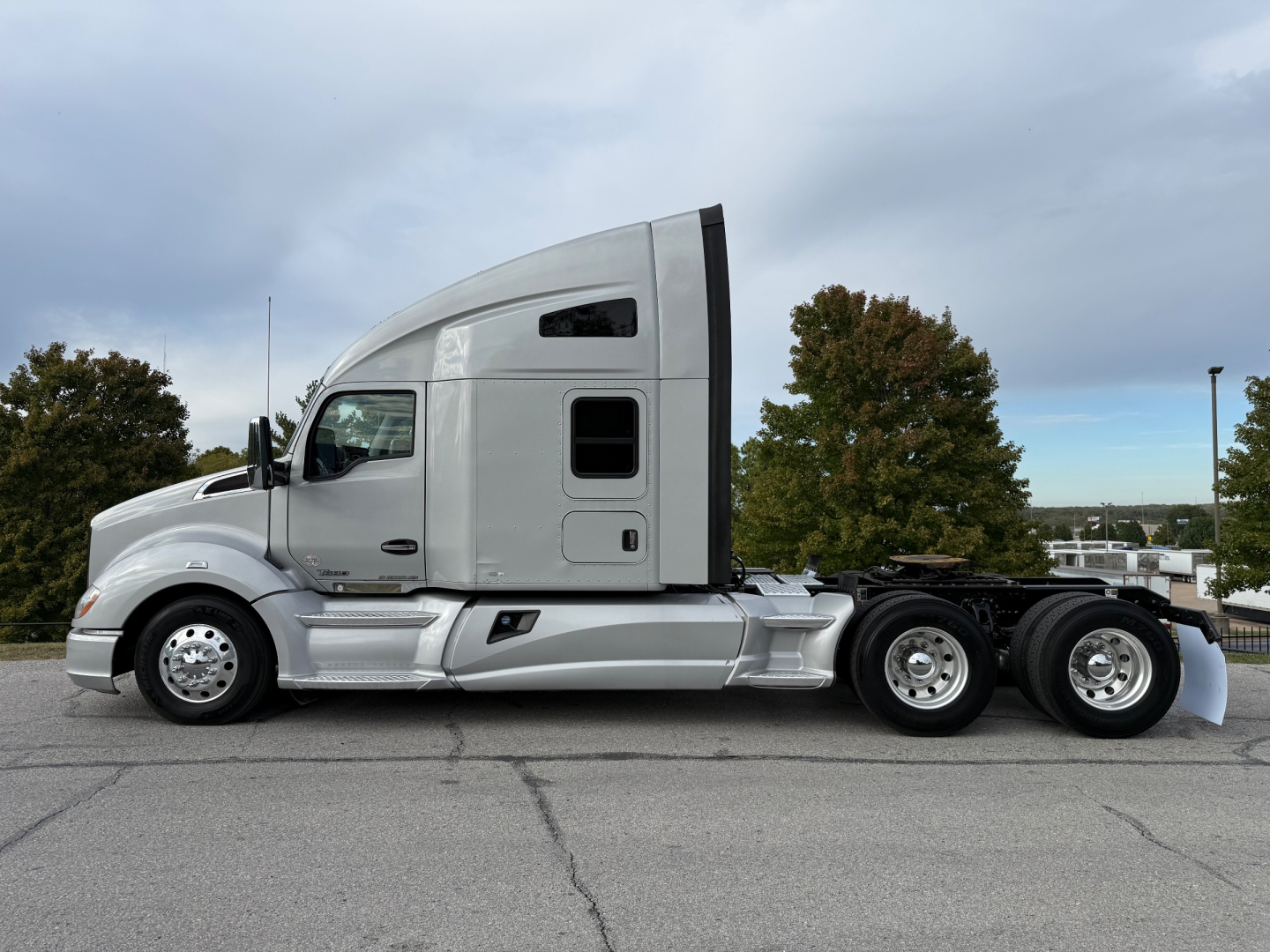 Kenworth T680 conventional sleeper tractor in side profile showing cab, fuel tanks, and dual rear axles with silver paint and chrome wheels.